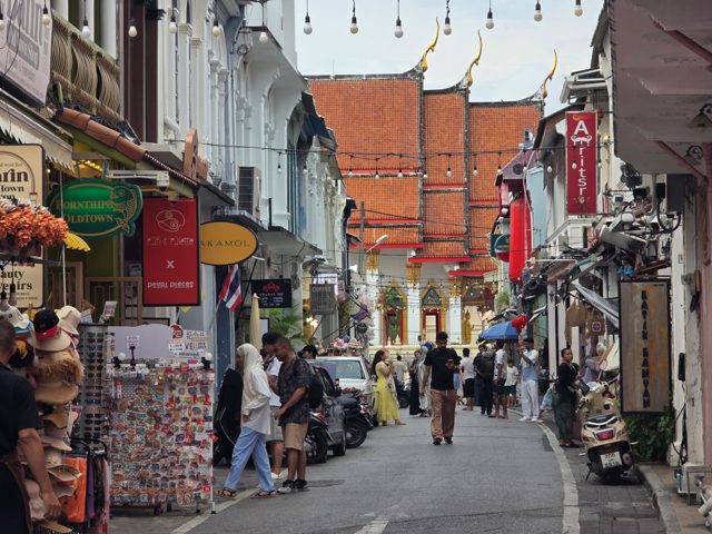 Pedestrians walking through a Phuket Old Town street lined with historic shopfronts